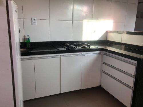 een keuken met witte kasten en een zwart aanrechtblad bij Casa e suítes da Vava in Trairi