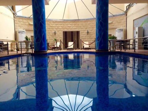 阿可賀巴的住宿－فندق كارم الخبر - Karim Hotel Khobar，一座建筑物内一座拥有蓝色柱子的游泳池
