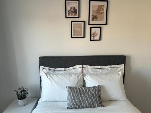 a bed with white pillows and framed pictures on the wall at Cozy home in Brampton (Mt pleasant Go station) in Brampton