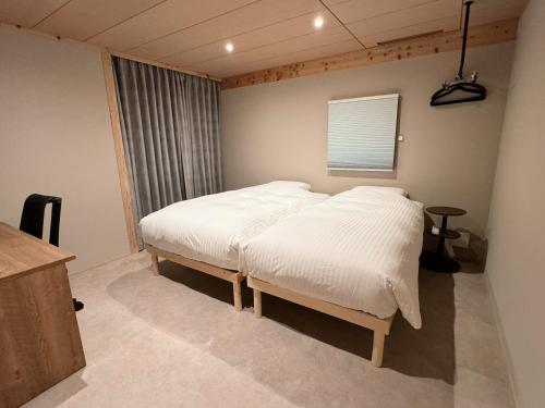 a bedroom with a bed with white sheets and a window at ARTISANAL in Naoshima
