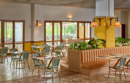 un restaurant avec des tables, des chaises et des fenêtres dans l'établissement Serenè Resort, à Steccato
