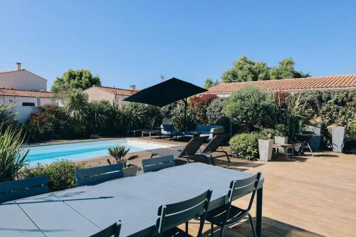 - une table avec des chaises et un parasol à côté de la piscine dans l'établissement ღ Le Paradis Bleu • Villa avec piscine chauffée, à LʼHoumeau