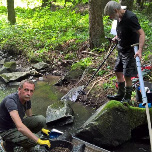 two men are standing on rocks in a creek at Apartmány U Orlického jezera - Kamenice in Klučenice