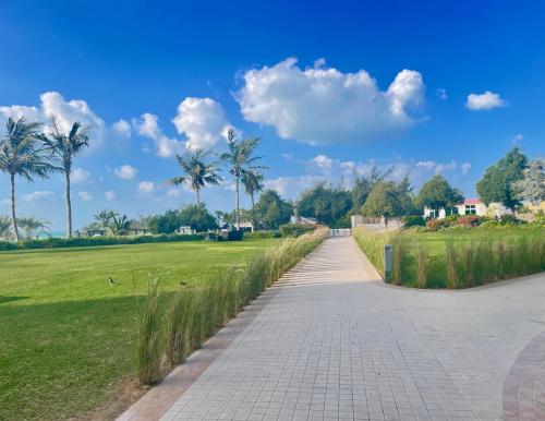 a path in a park with palm trees and grass at I Like Al Hamra Palace - Elite Beach & Golf Resort Private Suites in Ras al Khaimah