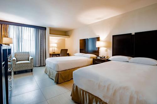 um quarto de hotel com duas camas e uma cadeira em Studio Coliving Hotel em Cidade do Panamá