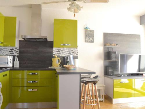 une cuisine avec des placards verts et un comptoir avec des tabourets dans l'établissement Appartement cosy à 200m de la plage, 2 pièces, 4 couchages - Narbonne Plage - FR-1-229B-76, à Narbonne