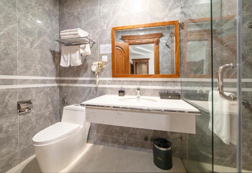 a bathroom with a toilet and a sink and a mirror at Royal Palace in Da Lat
