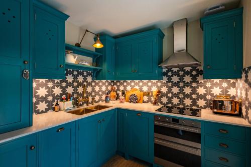 a kitchen with blue cabinets and stars on the wall at Stable Cottage, Gartocharn, Loch Lomond in Alexandria