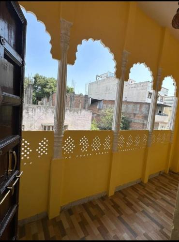 a room with a yellow wall with columns and a window at Hotel the ishani palace in Udaipur