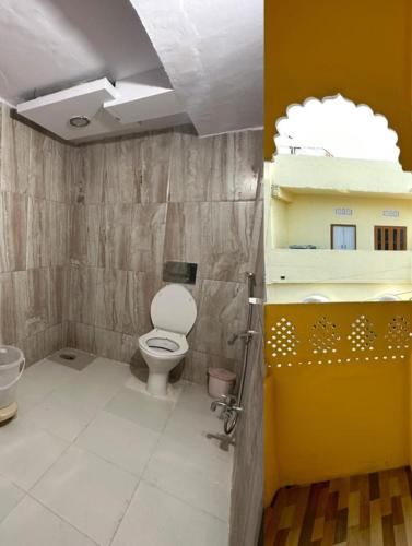 a bathroom with a toilet and a building on the wall at Hotel the ishani palace in Udaipur