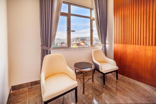 two chairs and a table in a room with a window at Royal Palace in Da Lat