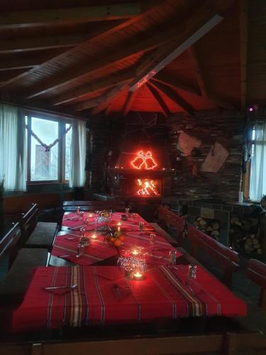 a dining room with a long table with red table cloth at Къща за гости с механа Баджо in Dospat