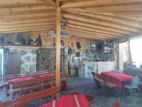 ein Esszimmer mit Tischen und Bänken in einem Gebäude in der Unterkunft Къща за гости с механа Баджо in Dospat