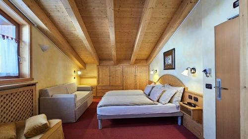 a bedroom with a bed and a couch and a window at Albergo Alpenrose in Livigno