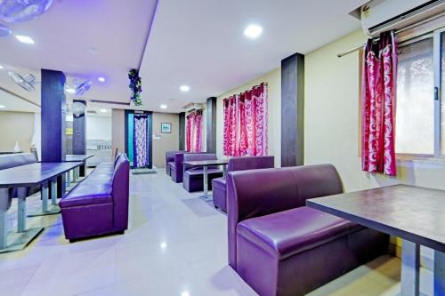 a waiting room with purple chairs and tables and windows at Cedar by K Hotels in Kāndūr