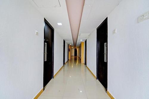 un largo pasillo con paredes blancas y puertas negras en Cedar by K Hotels, en Kāndūr