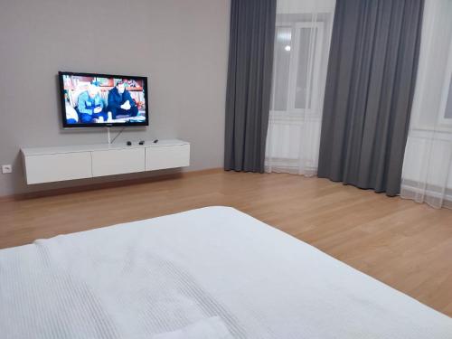 1 dormitorio con cama y vestidor con TV en Апартаменты Жаяу Мусы 7А, en Pavlodar