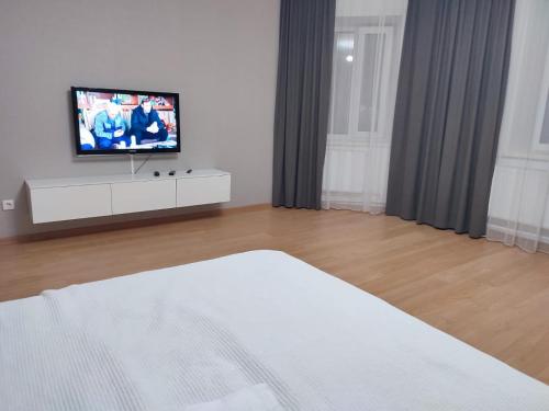 a bedroom with a bed and a tv on a dresser at Апартаменты Жаяу Мусы 7А in Pavlodar