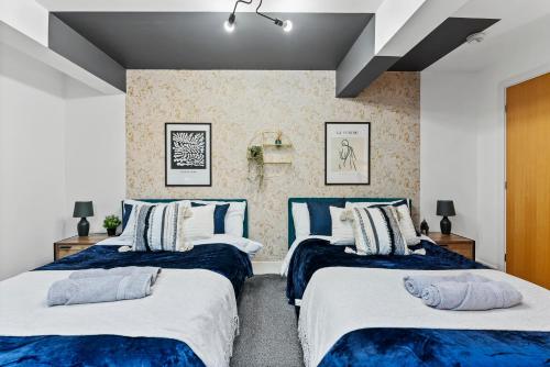 duas camas num quarto com azul e branco em Lovely Yorkshire Duplex - Sleeps 6 - Netflix em Dewsbury