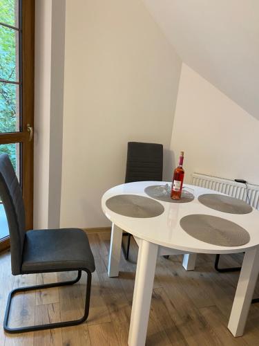 un tavolo bianco con una bottiglia di vino e una sedia di Jaren Karpacz a Karpacz