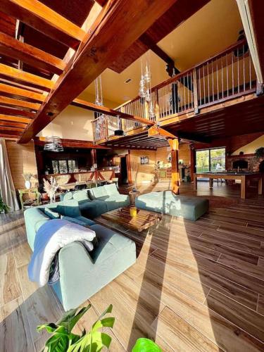 un grand salon avec des canapés bleus et un escalier dans l'établissement Chalet Acacia au calme 1h30 de Paris, à La Selle-en-Hermoy