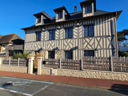 an old house with a fence in front of it at Villa d'exception, 5 chambres, 20m plage, spa. in Bénerville-sur-Mer