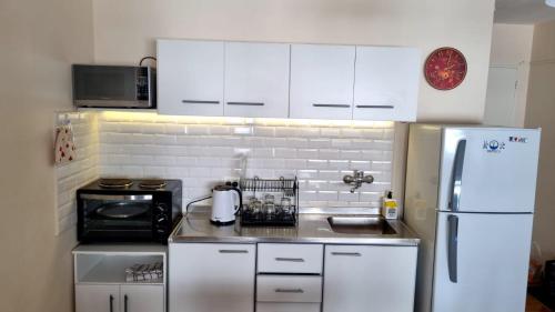La cuisine est équipée de placards blancs et d'un réfrigérateur blanc. dans l'établissement Departamento mejor ubicación Buenos Aires, à Buenos Aires