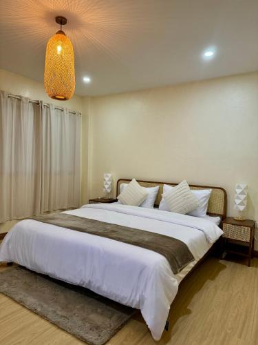 a bedroom with a large white bed with a chandelier at L’Oasis Nanai in Patong Beach
