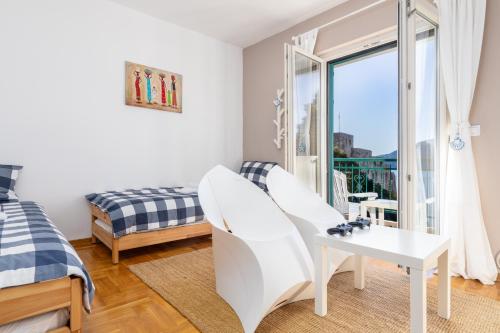 a bedroom with a bed and a white chair and a window at Lula la land (4 adults or family) in Herceg-Novi