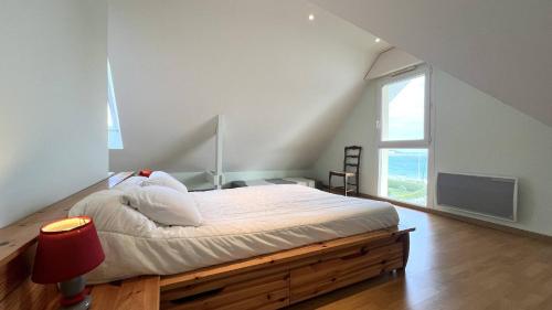 1 dormitorio con cama con marco de madera y ventana en 390 Appartement 3 chambres avec vue sur la Grande Plage de Saint-Cast, en La Garde