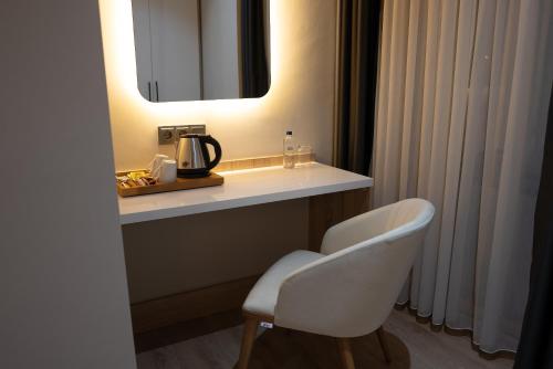 a bathroom with a sink and a mirror and a chair at Golden River Hotel By Continent in Arnavutköy