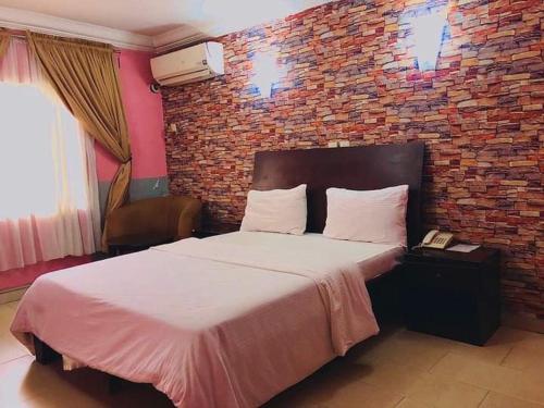 a bedroom with a large bed with a brick wall at BELIANA SUITES in Uyo