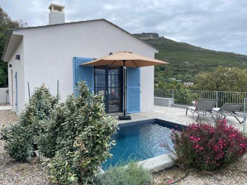 une maison avec une piscine et un parasol dans l'établissement Villa bellevue, neuve, 6 pax, pisc. chauffée, à Brando