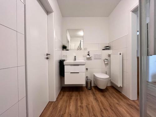 a white bathroom with a toilet and a sink at Aparthotel Tannenhof in Wittlich