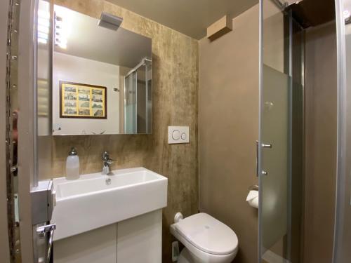 een badkamer met een wastafel, een toilet en een spiegel bij Monolocale Morimondo 1 in Milaan