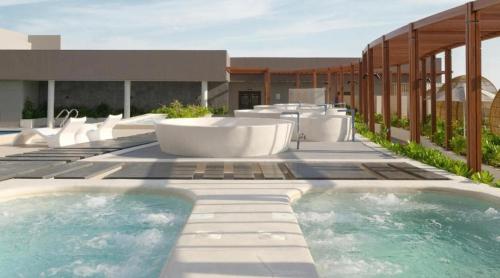 a swimming pool with white chairs and a building at Apec MANDALA CHAM BAY MUI NE SPA RESORT AND CONDOTEL in Ấp Thiẹn Ái