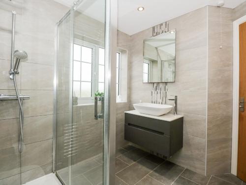 a bathroom with a shower and a sink and a mirror at Red Brick Cottage in Alford