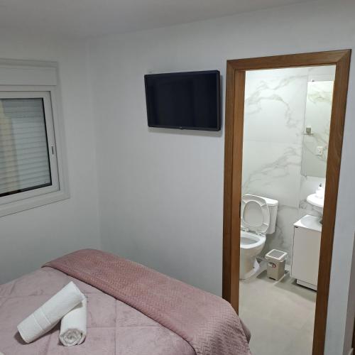 a bedroom with a toilet and a television on the wall at Casa Missões Dill Haus 1 in Gramado