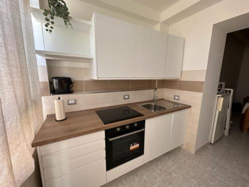 a kitchen with white cabinets and a stove and a sink at Affittacamere Il Cortile in Chiaravalle