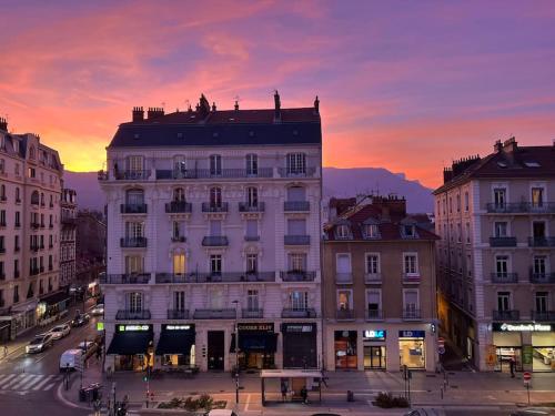 un grand bâtiment blanc avec un coucher de soleil en arrière-plan dans l'établissement Appartement entièrement rénové proche gare, à Grenoble