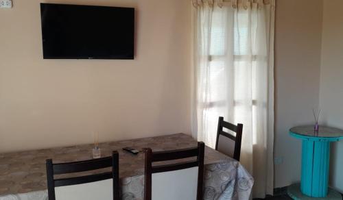 a dining room table with two chairs and a television on the wall at Casa Passiflora II in Villa Elisa