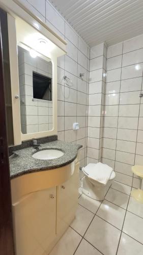 uma casa de banho com um lavatório, um WC e um espelho. em Apto Violetas na Janela- à 50m do Parque Termal em Piratuba