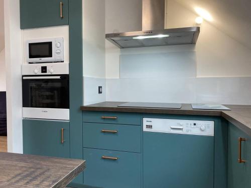 La cuisine est équipée de placards bleus et d'un four avec plaques de cuisson. dans l'établissement 211 - T3 entièrement rénové en plein centre de Plurien à moins de 5 minutes des Plages, à Plurien