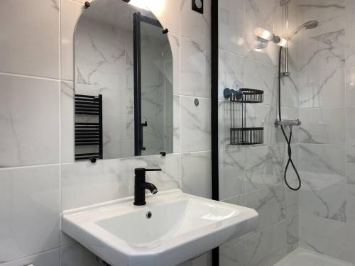 a white bathroom with a sink and a shower at 211 - T3 entièrement rénové en plein centre de Plurien à moins de 5 minutes des Plages in Plurien