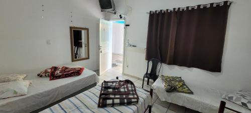 Cette chambre comprend 2 lits, une fenêtre et un miroir. dans l'établissement Recanto Azul, à Aparecida