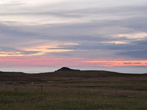 a hill in the middle of a field at sunset at Squealing Pig Bothy in Bragor