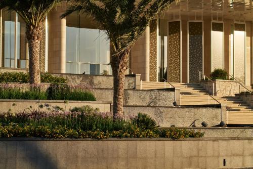 a building with palm trees and flowers in front of it at City of Dreams Mediterranean - Integrated Resort, Casino & Entertainment in Limassol