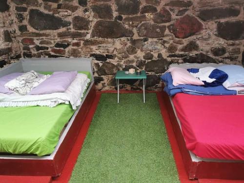 2 camas sentadas junto a una pared de ladrillo en Squealing Pig Bothy, en Bragor