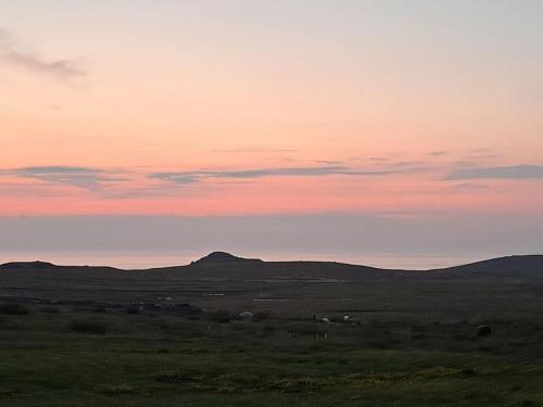 a sunset over a field with mountains in the distance at Squealing Pig Bothy in Bragor