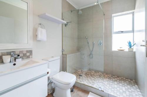 a white bathroom with a shower and a toilet at Green Point Living with Stadium View in Cape Town